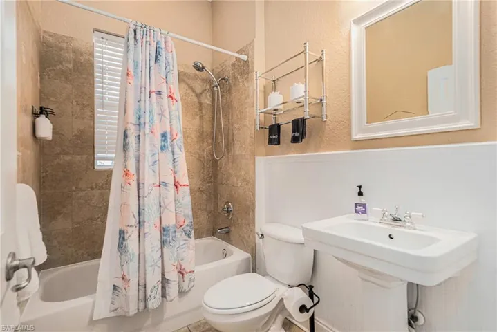 Full bathroom 2 with shower / tub combo, a textured wall, and a wainscoted wall