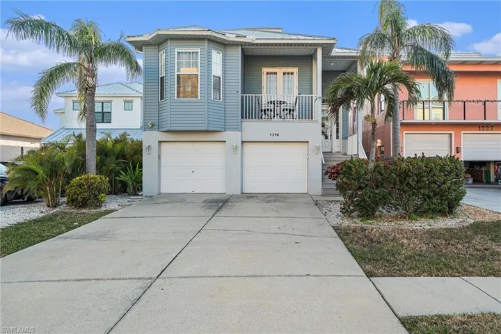 View of front of home with driveway, french doors, an attached garage, a balcony, and stucco siding