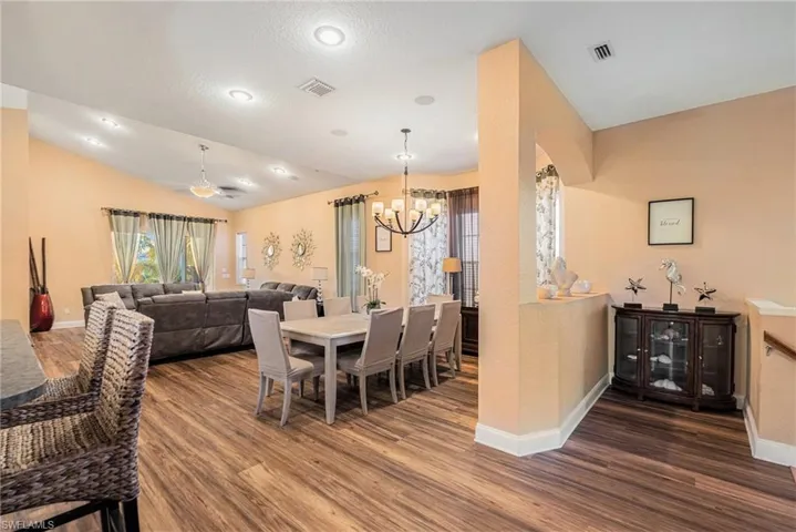 Dining space with vaulted ceiling, dark wood finished floors, a chandelier, ceiling fan, and recessed lighting