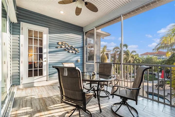 Screened lanai with a ceiling fan, outdoor dining area, overlooking pool, tiki hut and dock area