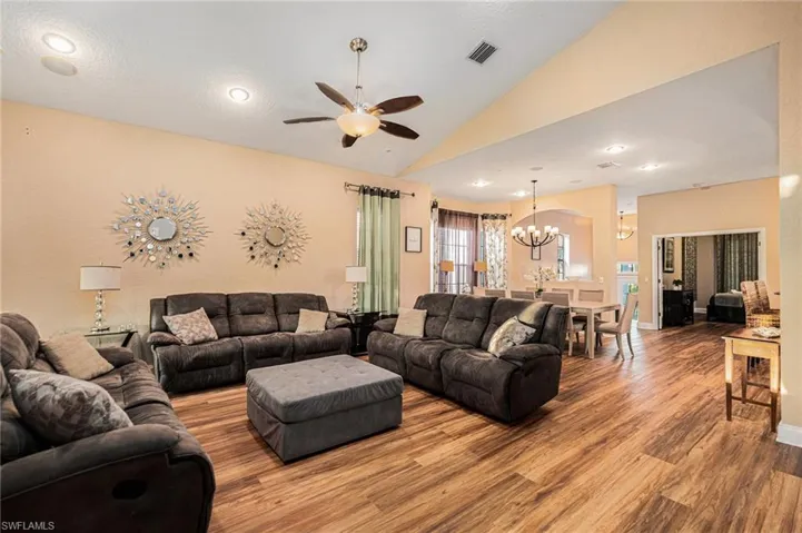 Living room with recessed lighting, vaulted ceiling, a chandelier, a ceiling fan, and wood finished floors
