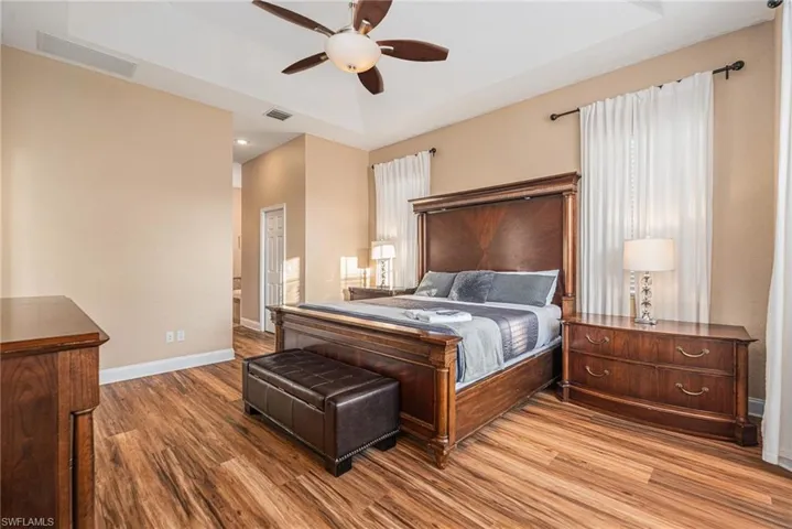 Bedroom featuring wood finished floors, ceiling fan, and a raised ceiling