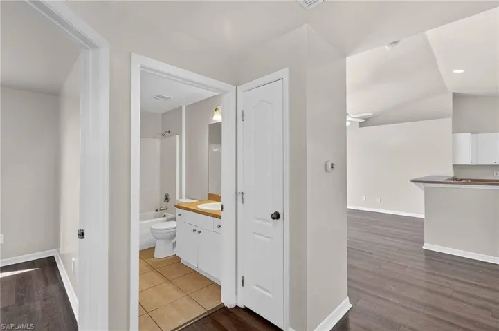 Bathroom featuring dark wood-style floors, vanity, bathing tub / shower combination, and vaulted ceiling