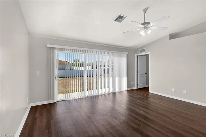 Empty room featuring a ceiling fan, lofted ceiling, and dark wood-style flooring