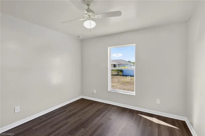 Unfurnished room with dark wood finished floors and ceiling fan
