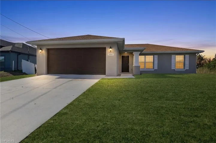 View of front facade with stucco siding, a garage, driveway, and a lawn