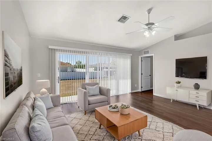 Living area featuring wood finished floors, vaulted ceiling, and a ceiling fan