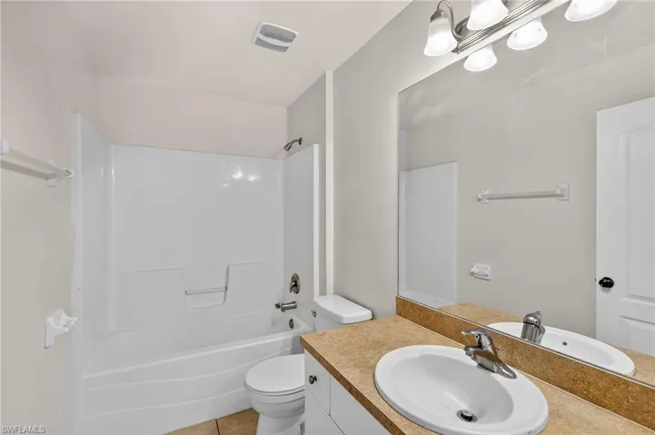 Bathroom featuring vanity, tub / shower combination, and light tile patterned flooring