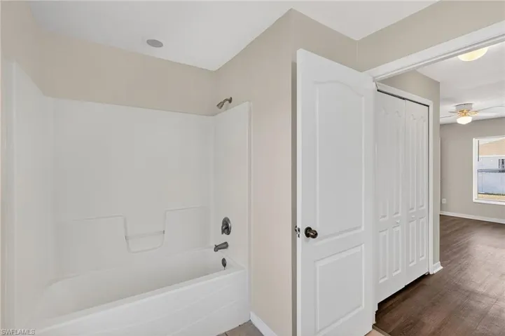 Full bathroom featuring ceiling fan, tub / shower combination, a closet, and wood finished floors