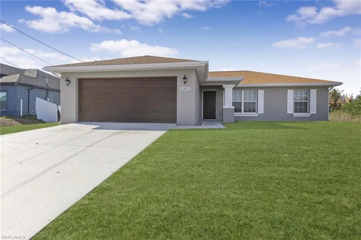 Ranch-style home featuring stucco siding, driveway, a garage, and a front lawn