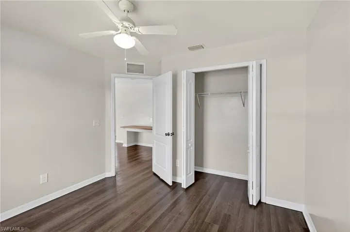 Unfurnished bedroom with dark wood-style floors, a ceiling fan, and a closet