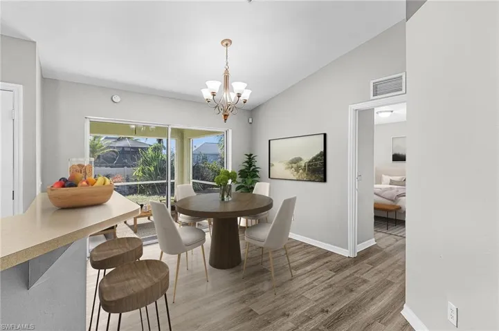 Dining room with vaulted ceiling, light wood-style floors, and a chandelier
