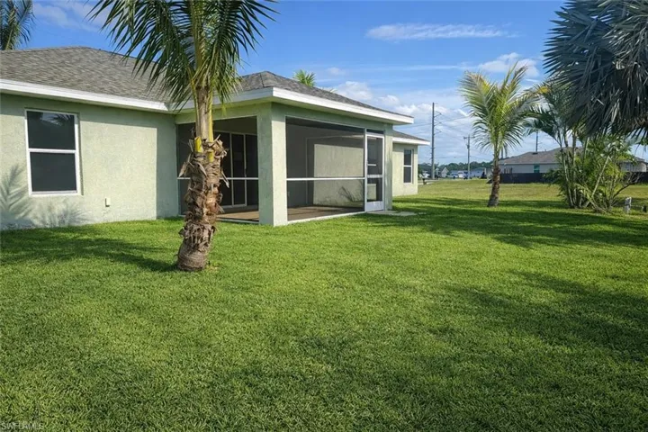Back of house featuring stucco siding, a lawn, a sunroom, and roof with shingles