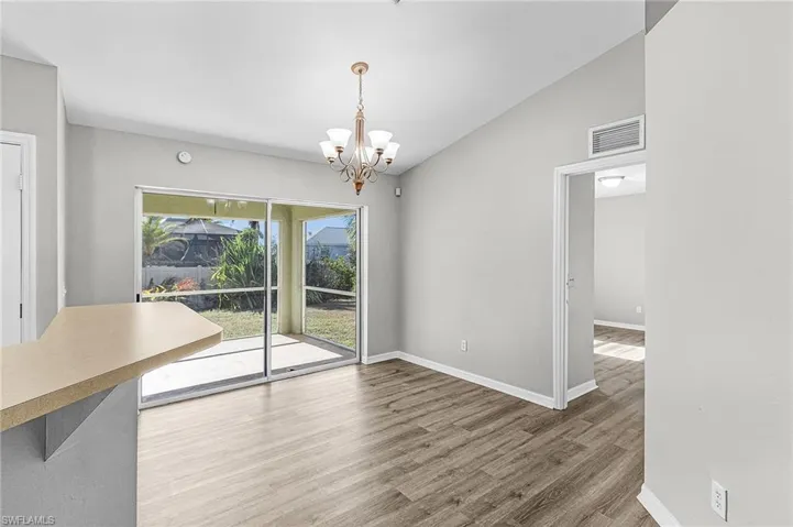 Unfurnished dining area with lofted ceiling, light wood finished floors, and a chandelier