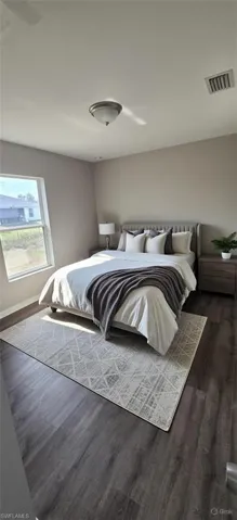 Bedroom with dark wood-style floors and baseboards