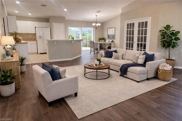 Living area with lofted ceiling, dark wood-style floors, a chandelier, and recessed lighting