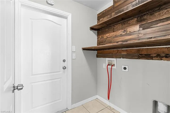 Laundry room with hookup for a washing machine, light tile patterned flooring, and electric dryer hookup