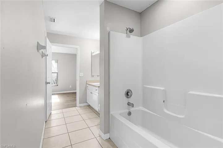 Full bath with bathtub / shower combination, vanity, and light tile patterned floors
