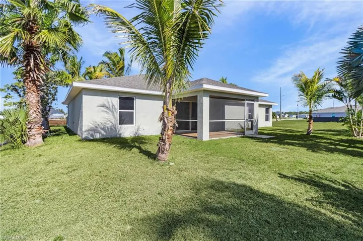 Back of property featuring a yard, stucco siding, and a sunroom