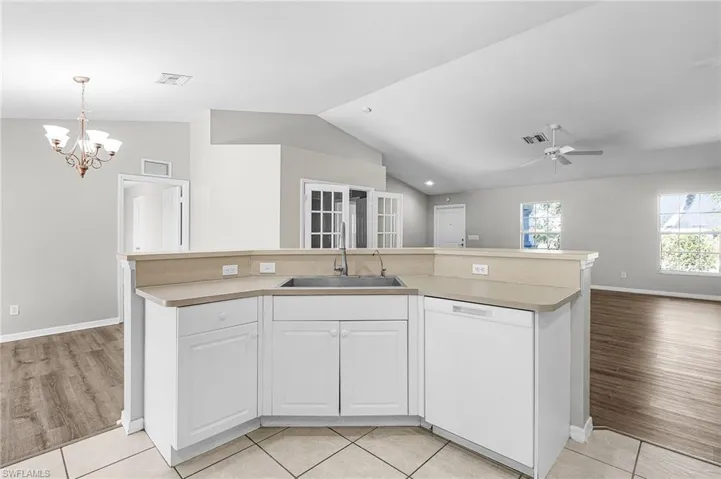 Kitchen with white cabinets, dishwasher, an island with sink, open floor plan, and light countertops