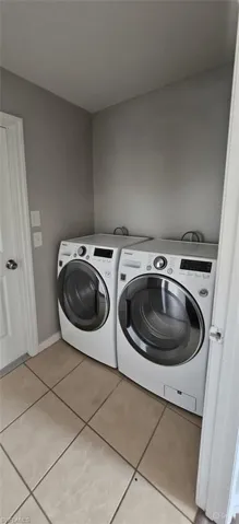 Washroom featuring light tile patterned flooring and washer and dryer