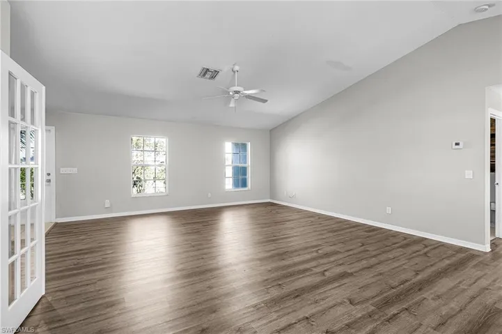 Spare room featuring vaulted ceiling, dark wood-style flooring, and ceiling fan