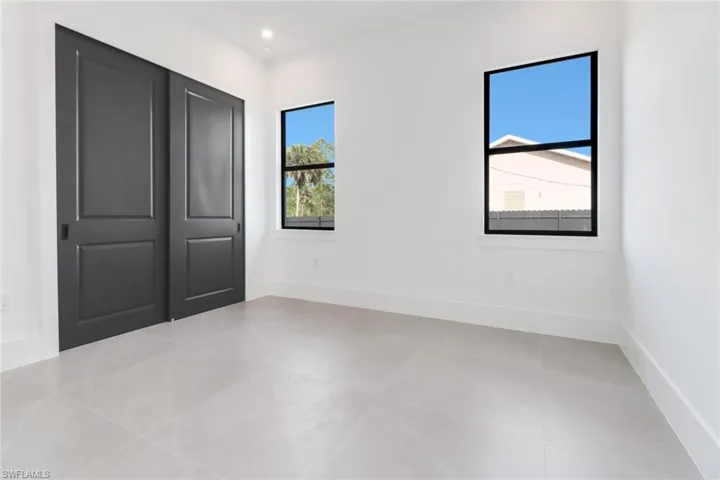 Unfurnished bedroom with a closet, light tile patterned flooring, and multiple windows