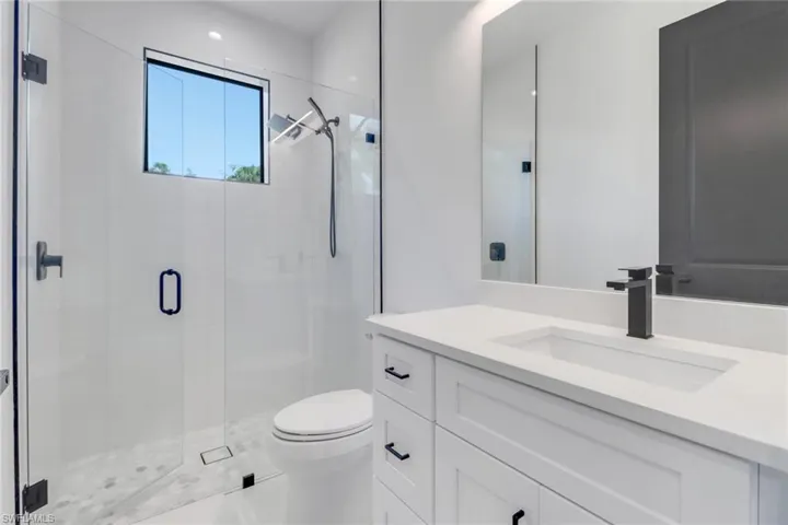 Bathroom with vanity, toilet, and a shower with shower door