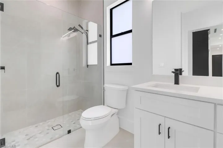 Bathroom with vanity, toilet, and an enclosed shower