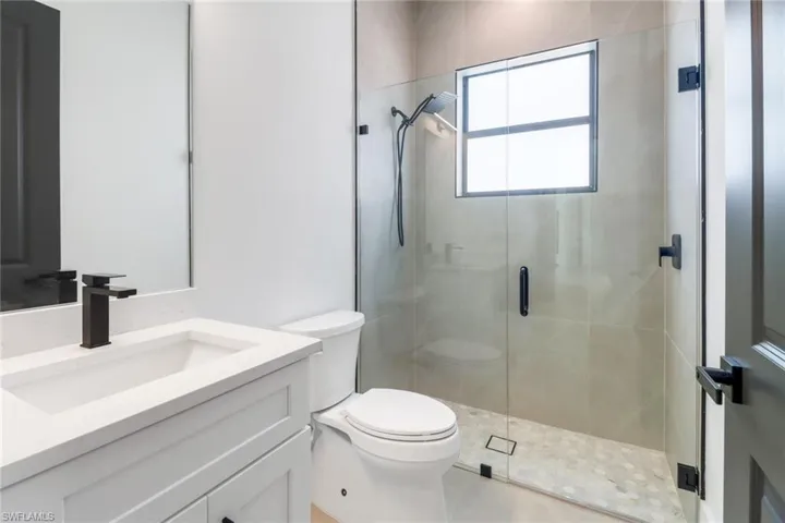 Bathroom with tile patterned floors, vanity, toilet, and a shower with door