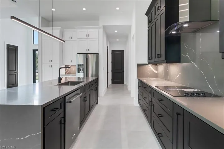 Kitchen with backsplash, stainless steel appliances, sink, wall chimney range hood, and white cabinets