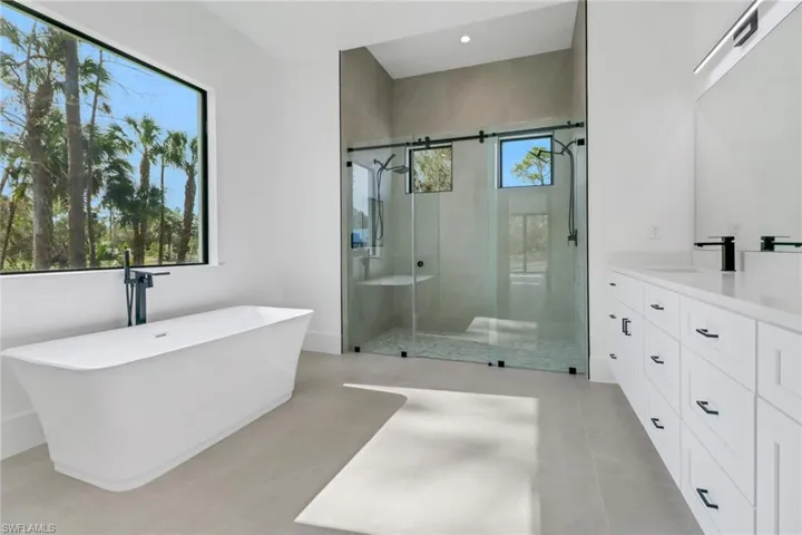 Bathroom featuring tile patterned flooring, shower with separate bathtub, and vanity
