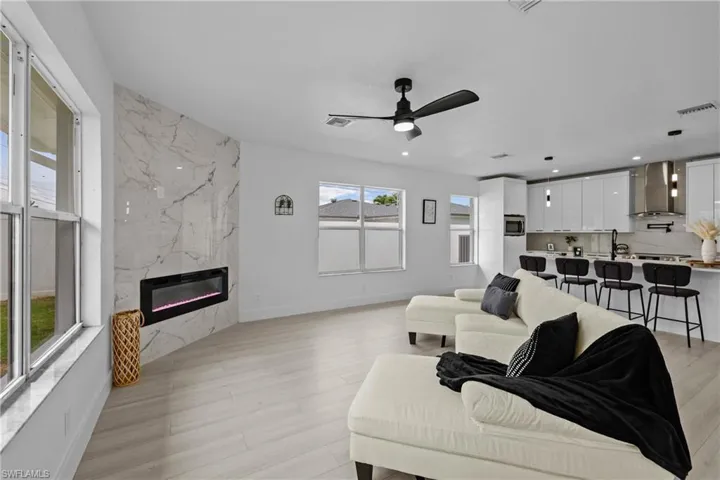 Living room with ceiling fan, a fireplace, and light wood-type flooring