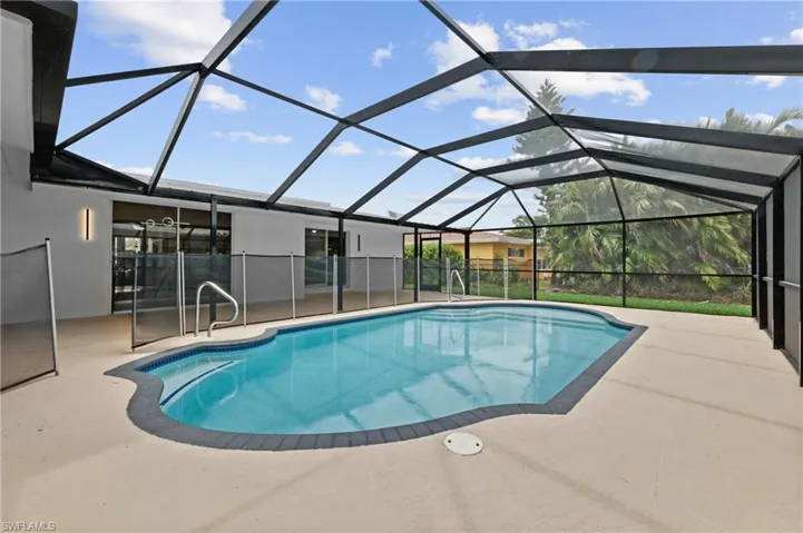 View of pool featuring a patio area and glass enclosure