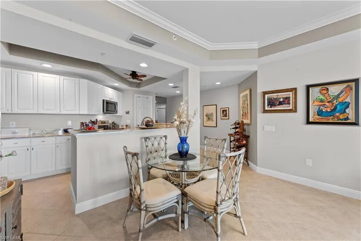 Dining space featuring ornamental molding, light tile patterned floors, ceiling fan, and a raised ceiling