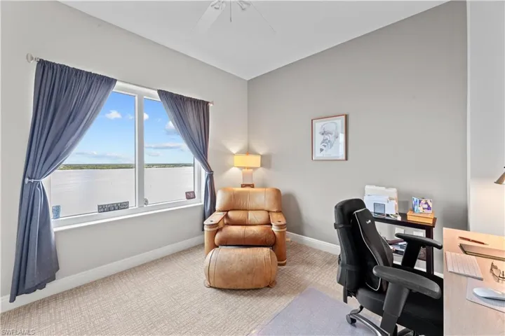 Carpeted home office featuring ceiling fan