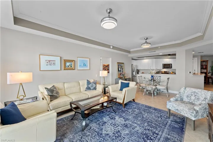 Tiled living room with crown molding and a tray ceiling