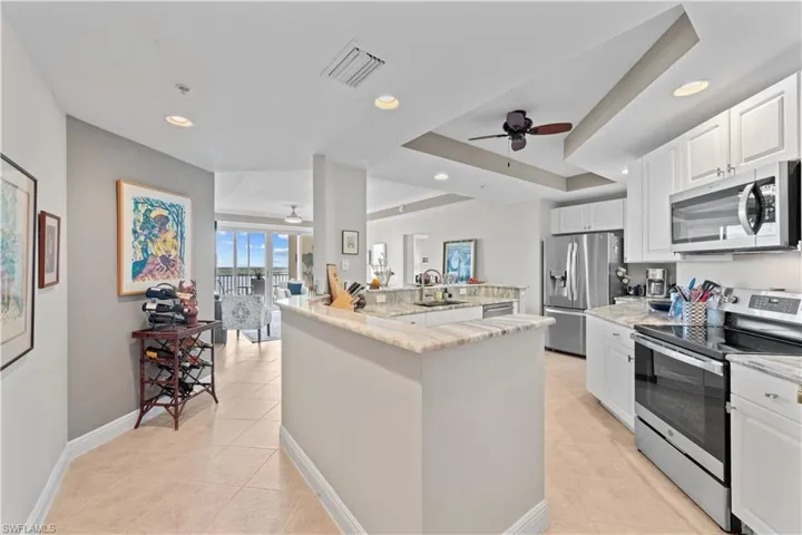 Kitchen with ceiling fan, white cabinets, sink, appliances with stainless steel finishes, and light tile patterned floors