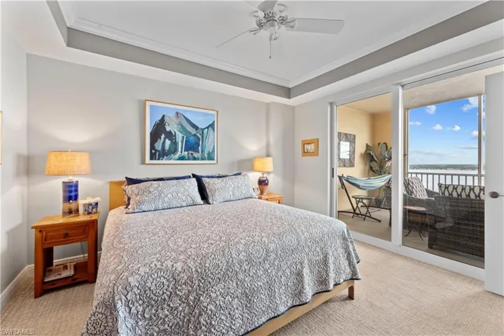 Carpeted bedroom with a raised ceiling, access to outside, ornamental molding, and ceiling fan