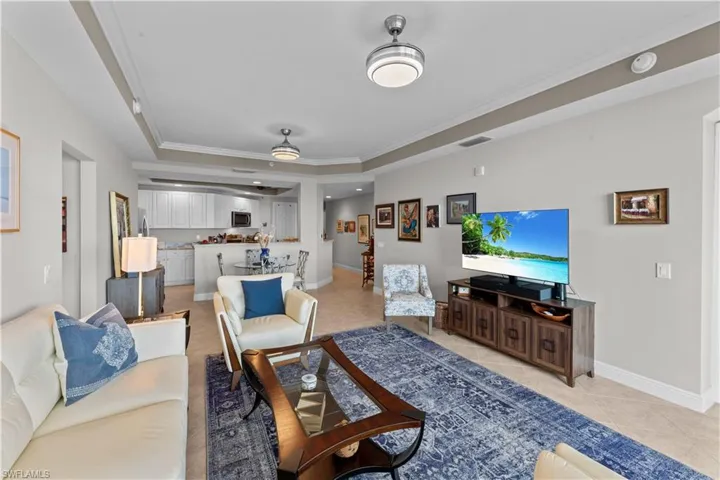 Living room featuring a tray ceiling, ornamental molding, and light tile patterned floors