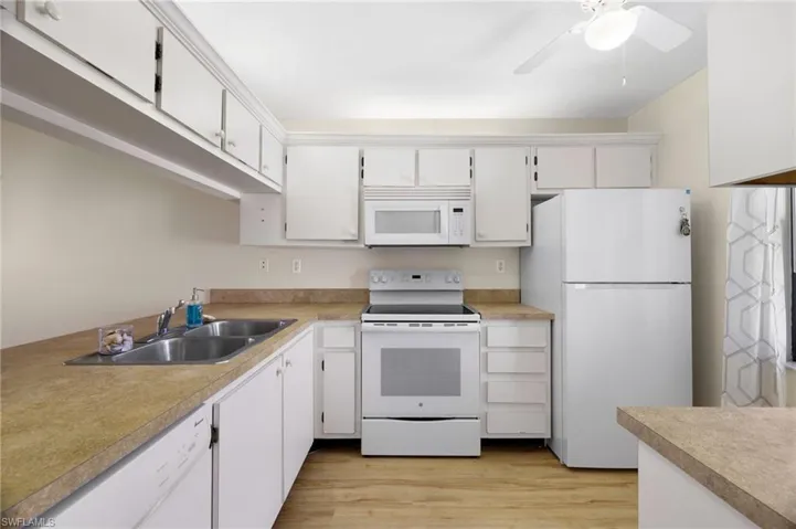 Kitchen featuring white appliances, white cabinets, and light countertops