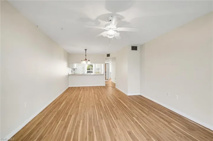 Unfurnished living room with light wood-style floors, ceiling fan, and a chandelier