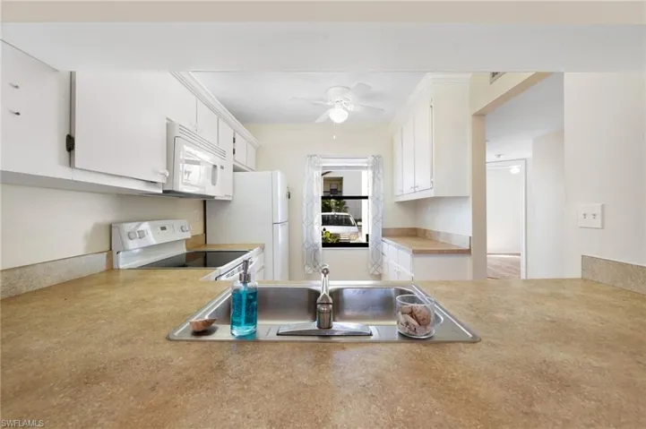 Kitchen featuring light countertops, white appliances, white cabinetry, and ceiling fan