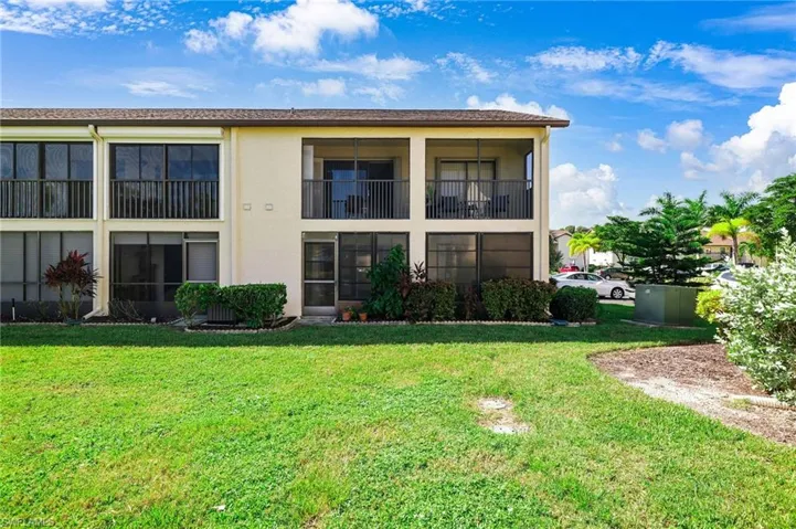 Rear view of property featuring a sunroom, a yard, stucco siding, and a balcony