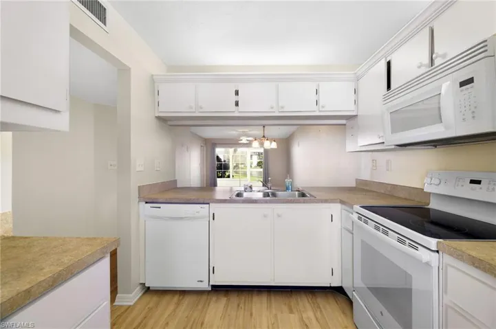Kitchen with white appliances, white cabinets, light wood finished floors, and light countertops