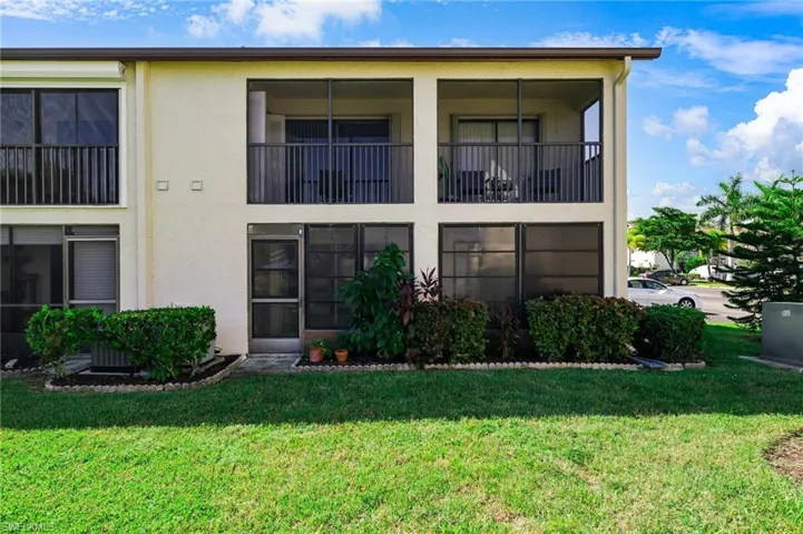 Back of property featuring stucco siding, a yard, a sunroom, and a balcony