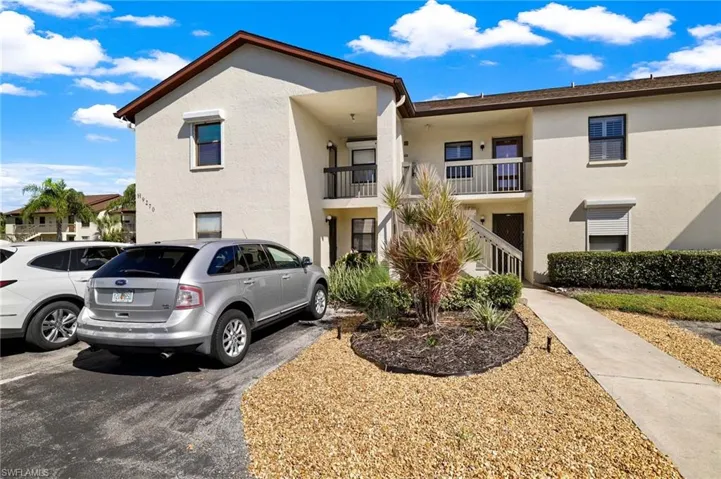 View of front facade featuring stucco siding, uncovered parking, and a balcony