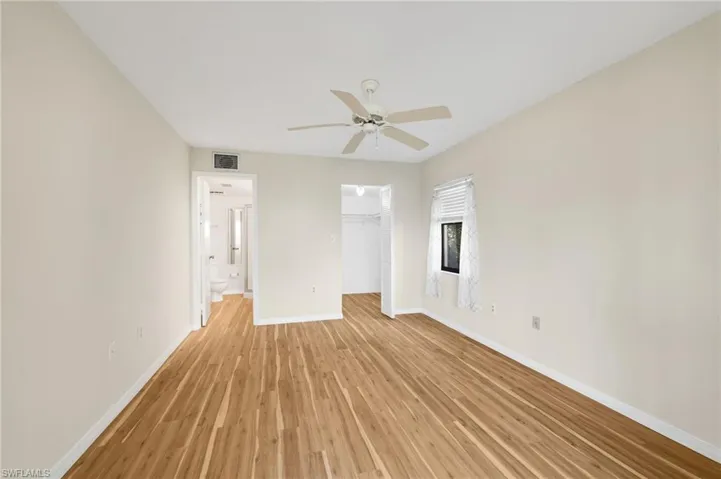 Unfurnished bedroom with light wood finished floors, a spacious closet, and a ceiling fan
