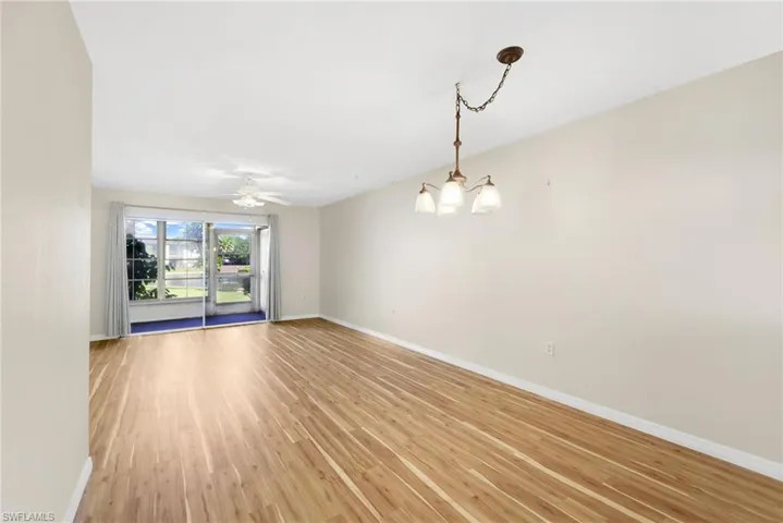 Empty room with light wood-style flooring, ceiling fan, and a chandelier