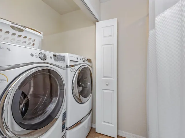 Washroom featuring light tile patterned floors, laundry area, independent washer and dryer, and baseboards